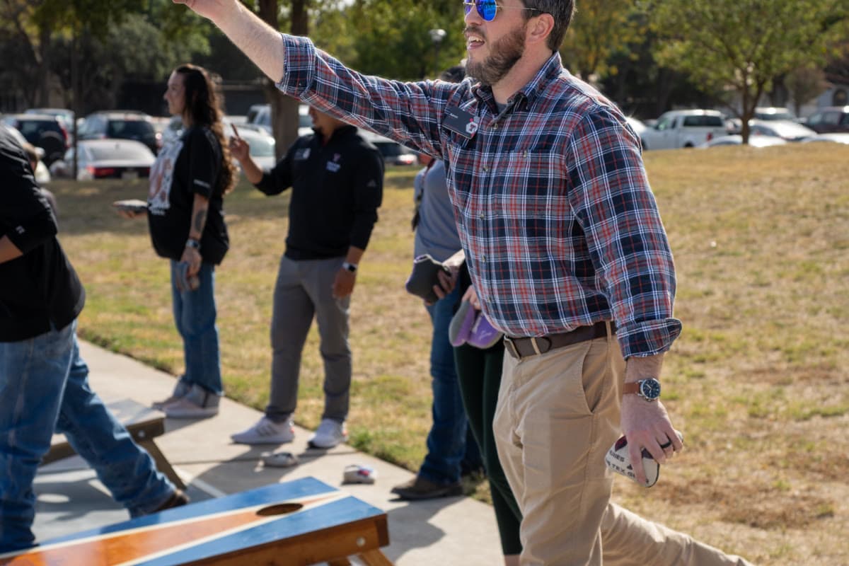 Competitors throw cornhole bean bags during the SECC Cornhole Tournament on an outdoor court