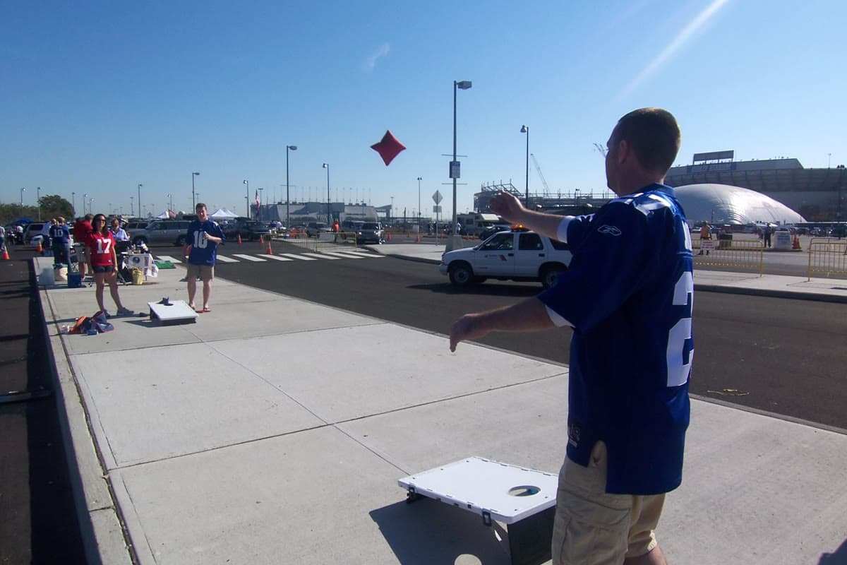 Cornhole boards set up on grass with bean bags at an outdoor tailgate party