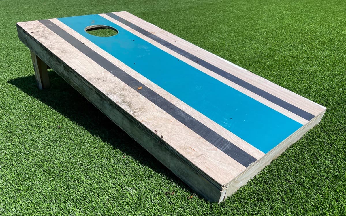 Striped custom cornhole board with a regulation hole set up outdoors in San Diego