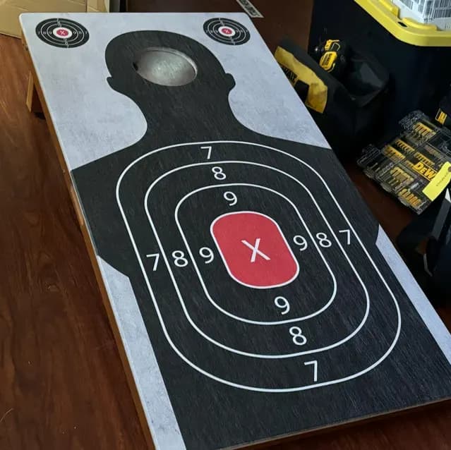 Cornhole board printed as a silhouette shooting target with scored rings, a red X, and two small bullseyes by the hole