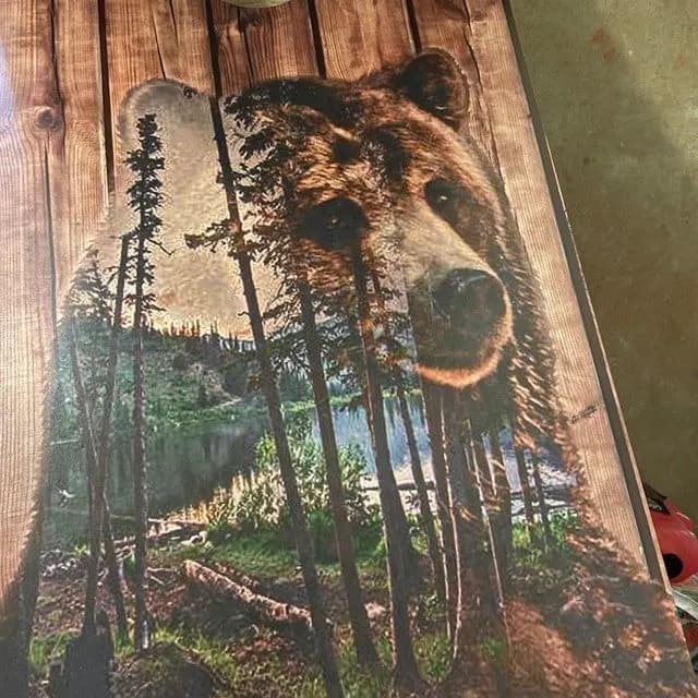 Wood-grain cornhole face printed with a double-exposure brown bear over a forest lake