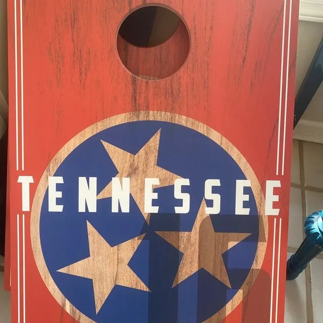 Red wood-grain cornhole board printed with a blue circle of three stars and the word Tennessee