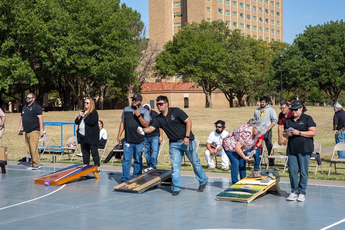 A team throwing bags across several cornhole boards at an organized outdoor tournament